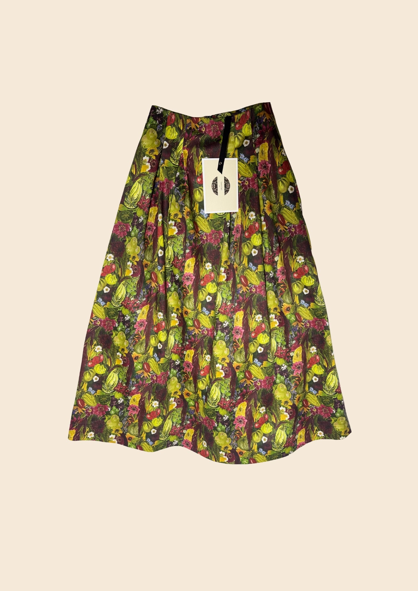 Flat lay image of the Vegetable Print August skirt created for August Beth to wear at RHS Chelsea, in her Around the world in 80 seeds Vegetable Emporium Alitex greenhouse takeover.  Designed by Lorelei London Sustainable brand made in the UK Hand drawn prints. Wearable stories. Timeless pieces to treasure.